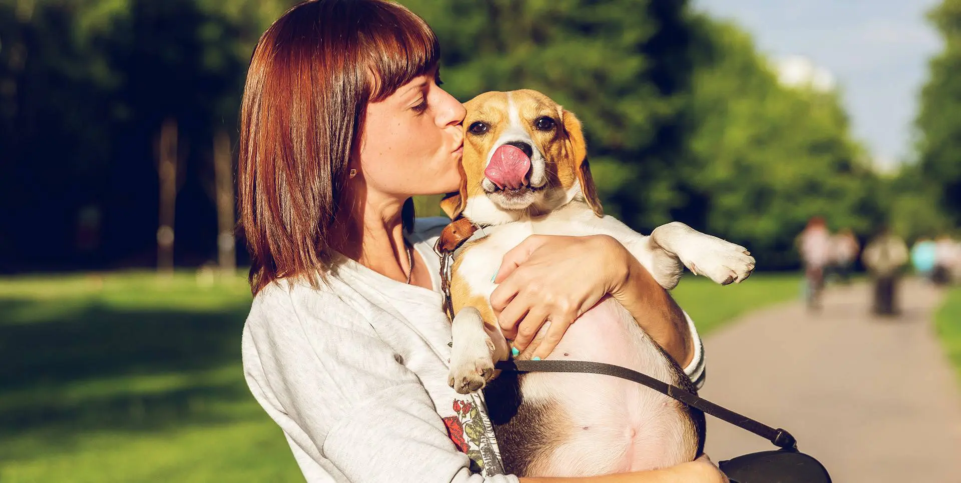 A woman kissing her dog on the cheek.