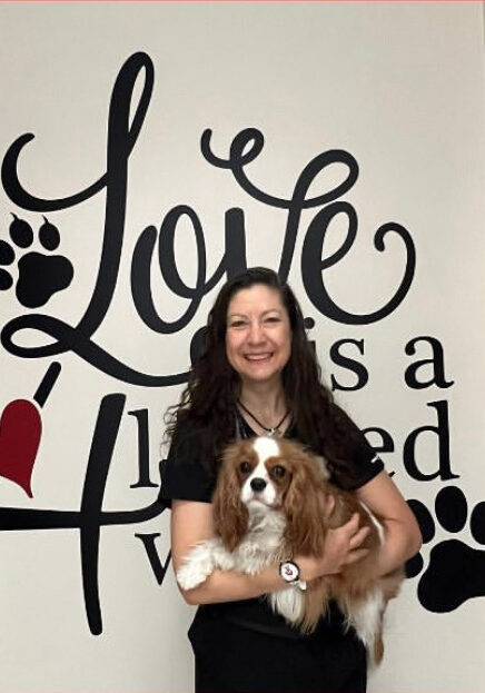 A woman holding her dog in front of a wall with the words " love is a breed ".