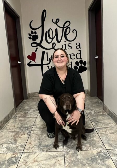 A woman kneeling down next to her dog.